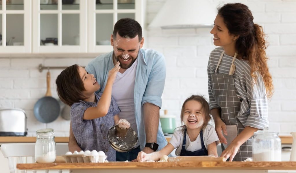 happy married couple baking in the kitchen with their children