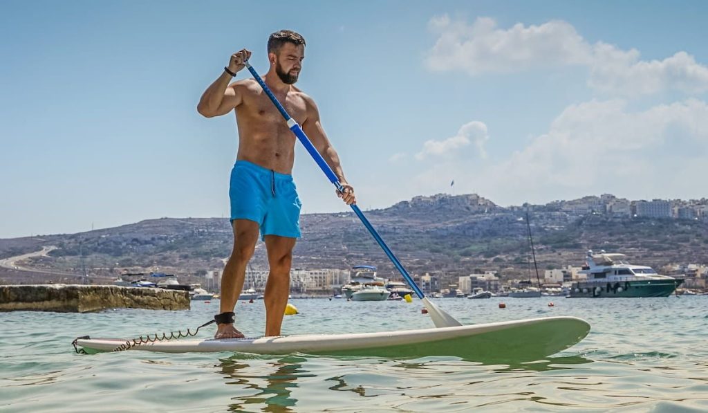 man on a paddle board near a port