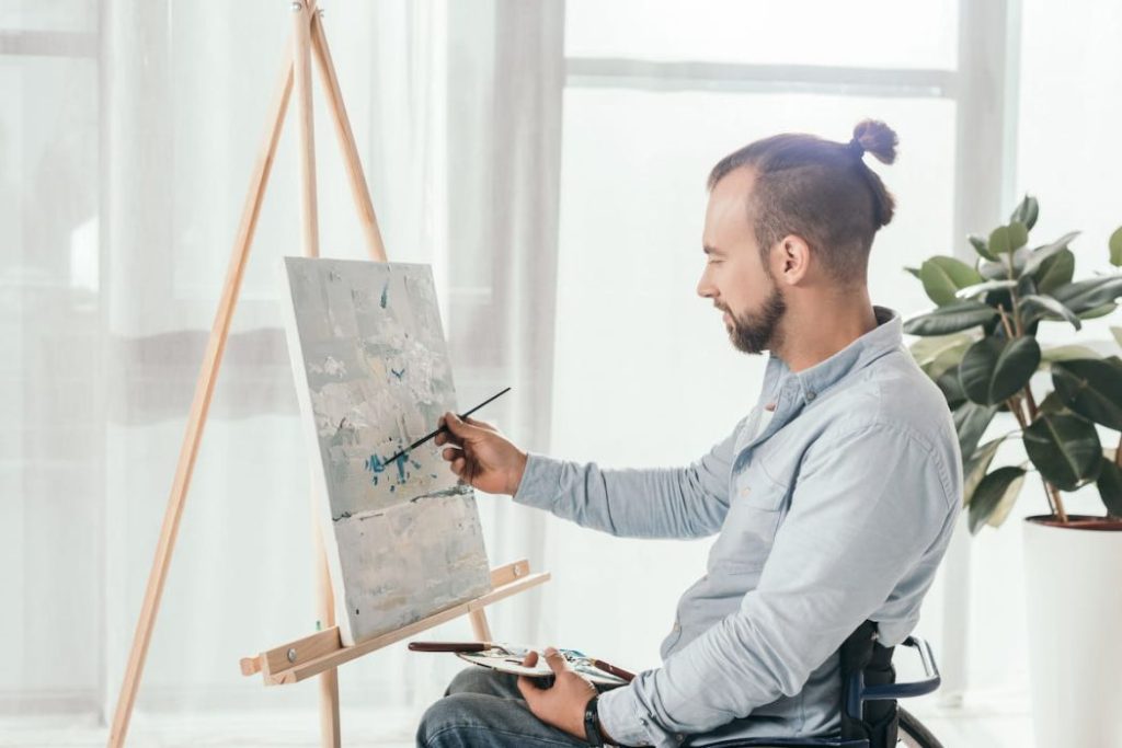 man on wheelchair painting something abstract