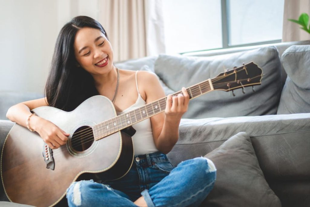 woman playing acoustic guitar musical instrument at home