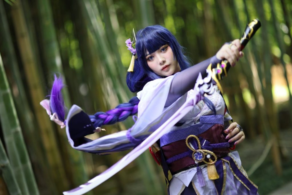 beautiful young woman cosplaying wearing a samurai dress costume and holding a sword at a Japanese garden