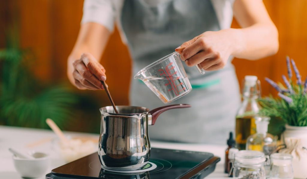 woman stirring up liquid solutions for making soap at home