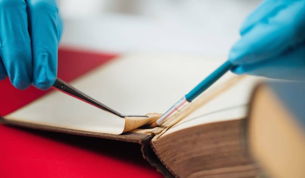 Book restorer repairing damaged pages in an antique book