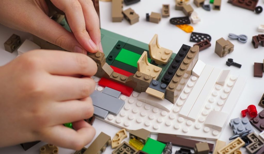 Child placing a Lego brick on to a Lego plate