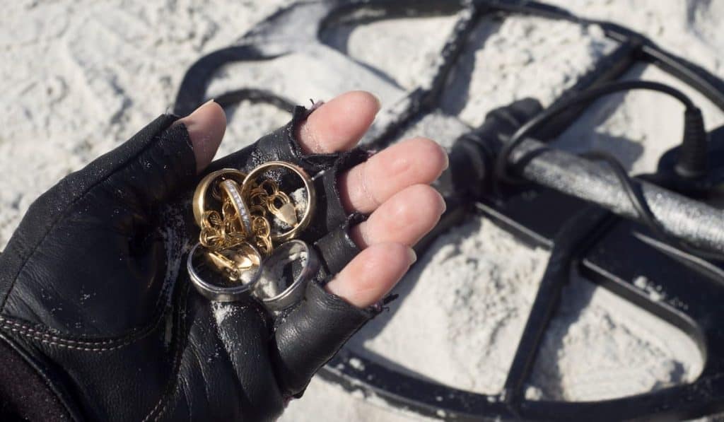 Metal detectorist holds jewelry found by metal detector 
