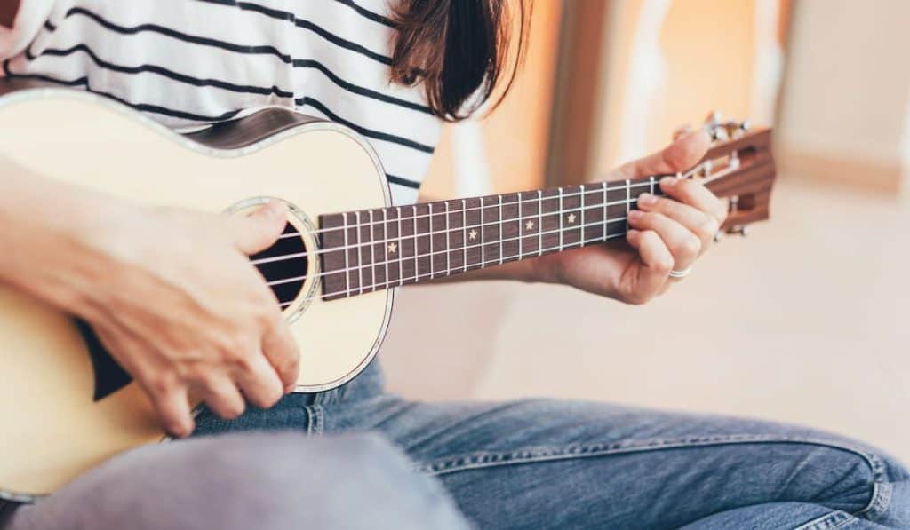 Woman play a song on ukulele, close-up musical instrument.