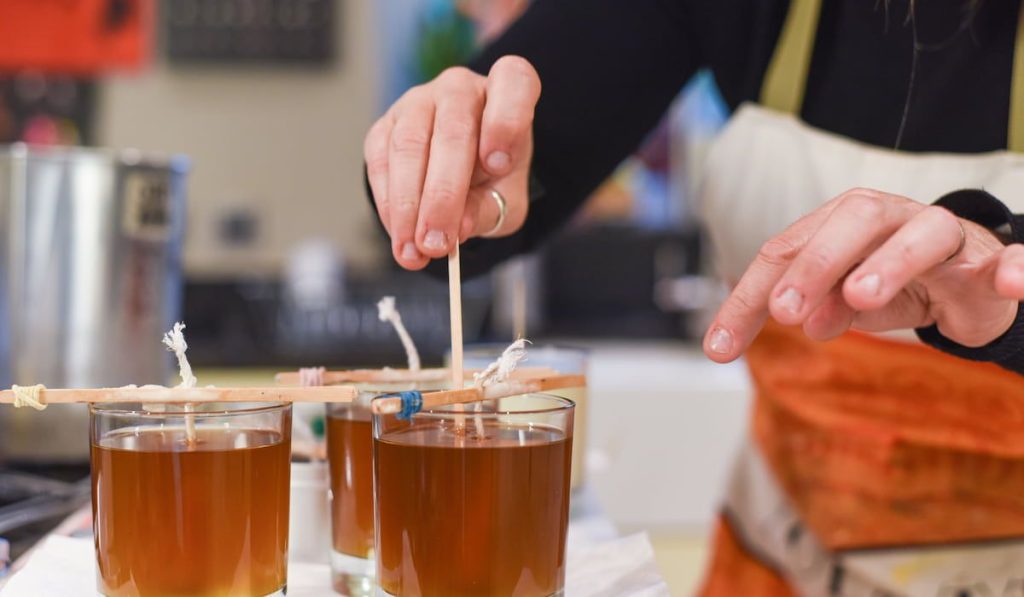 candle making showing the pouring of liquid wax into jars