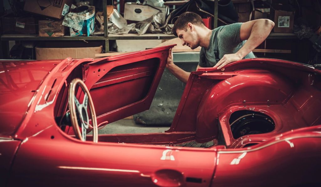 Mechanic working on car body details in restoration workshop