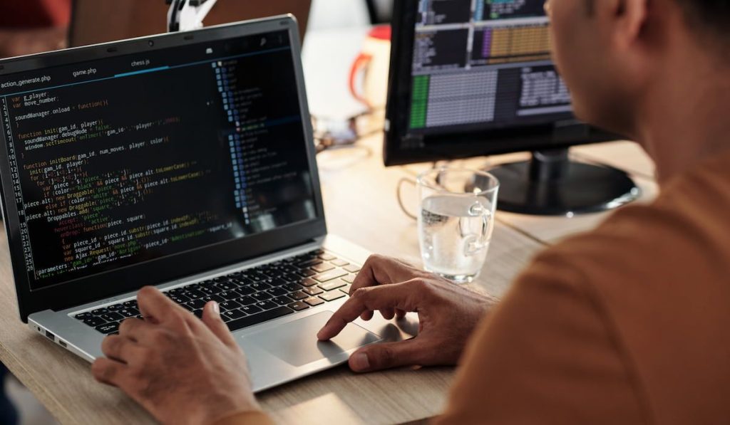 a man coding on laptop and reviewing code for mistakes