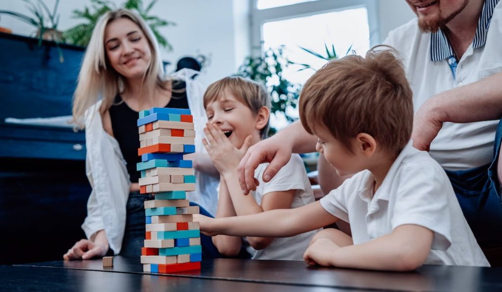 Happy couple and their children at home playing board game