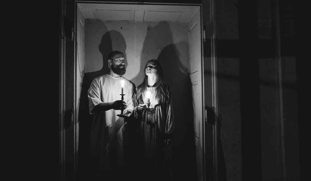 a man and a woman hold candle for ghost hunting
