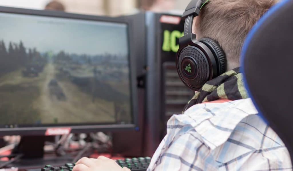 Young boy sits on gaming chair and plays game on PC