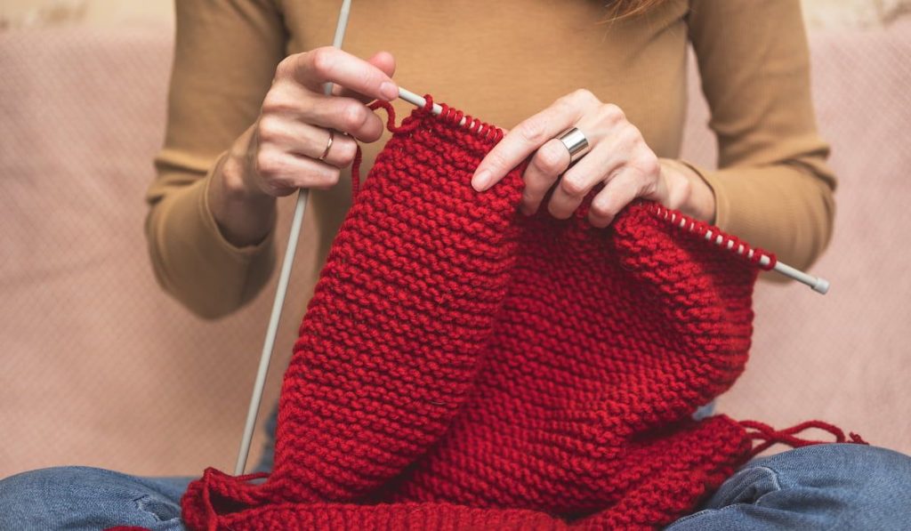 girl knits a red scarf