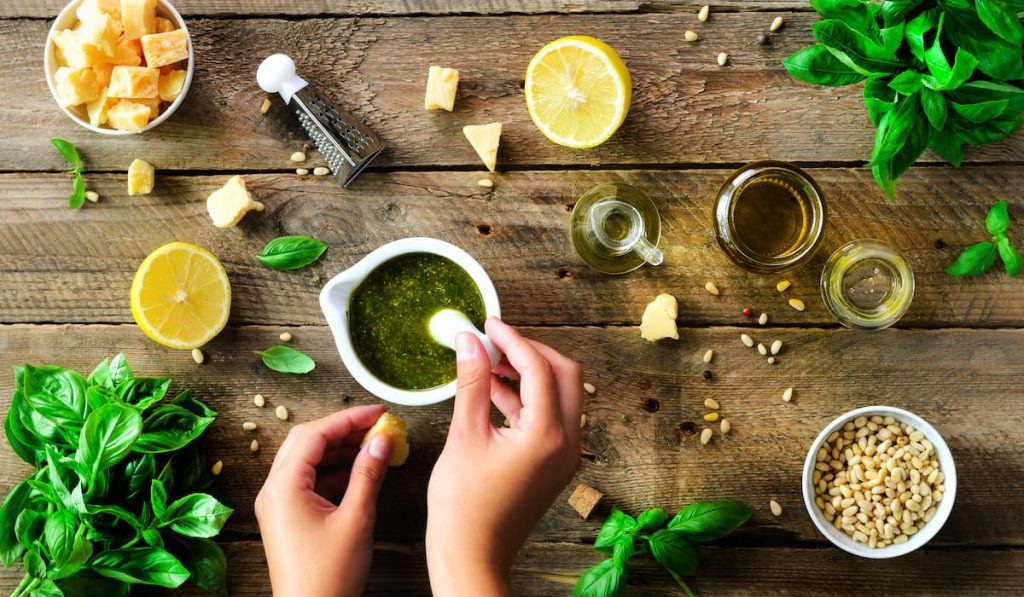 Woman hands making italian pesto sauce in bowl