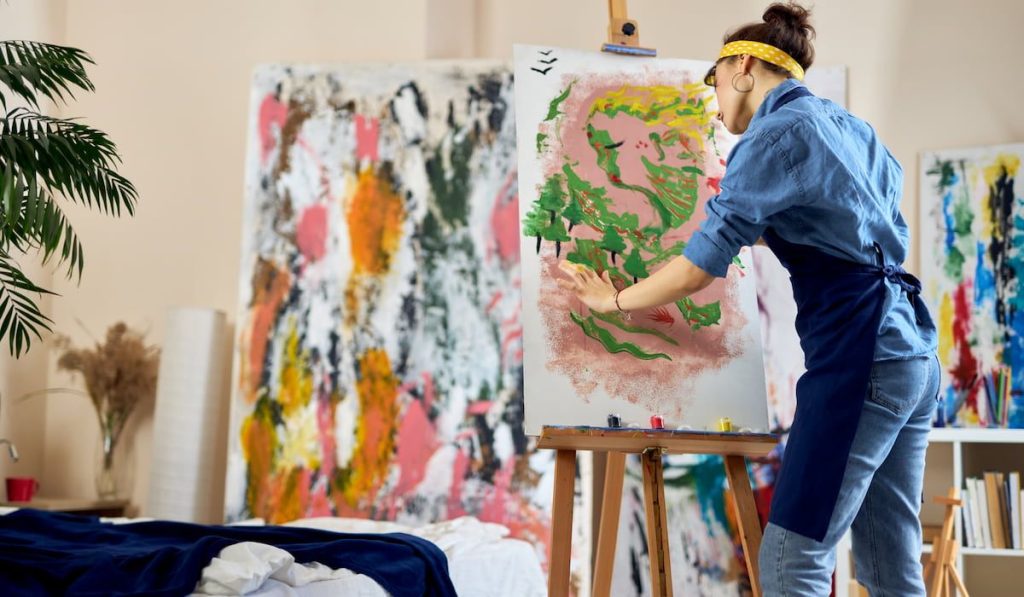 female artist looking inspired while creating her own abstract painting