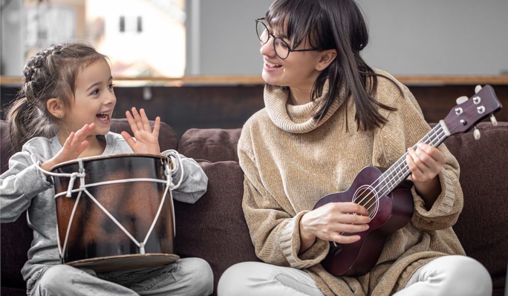 woman with her daughter have fun playing musical instruments at home