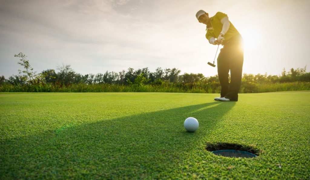 Golfer putting golf ball on the green golf