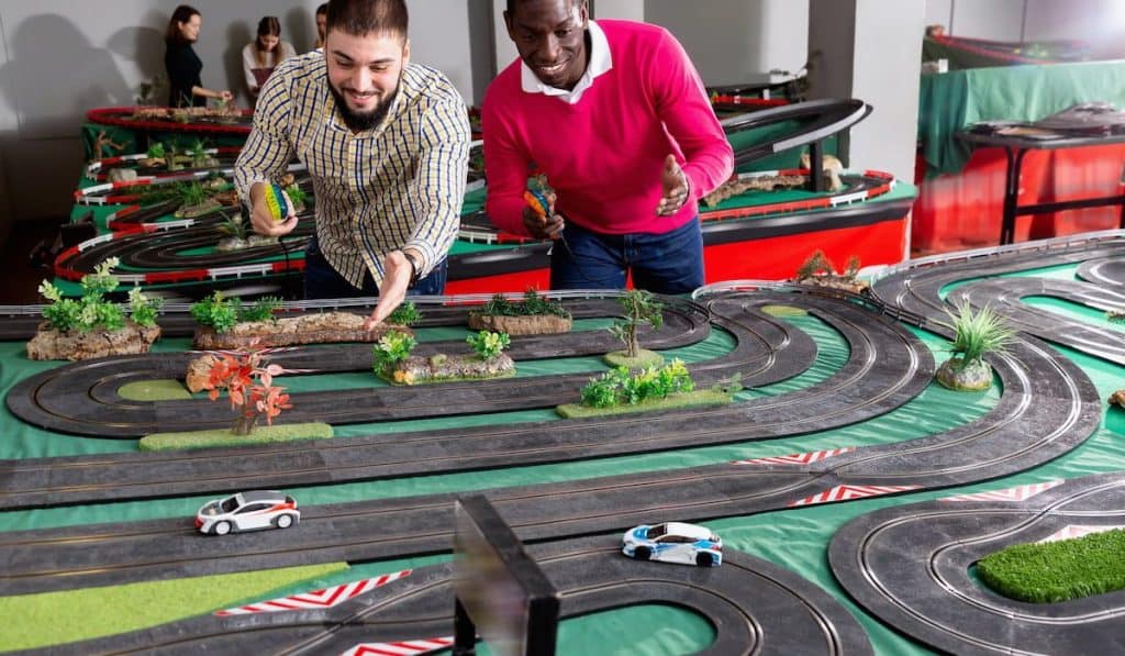 Two men playing with children slot car racing track