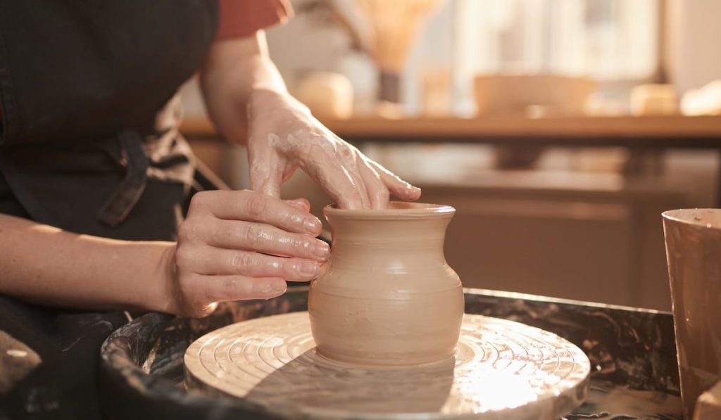 female hands shaping clay on pottery wheel