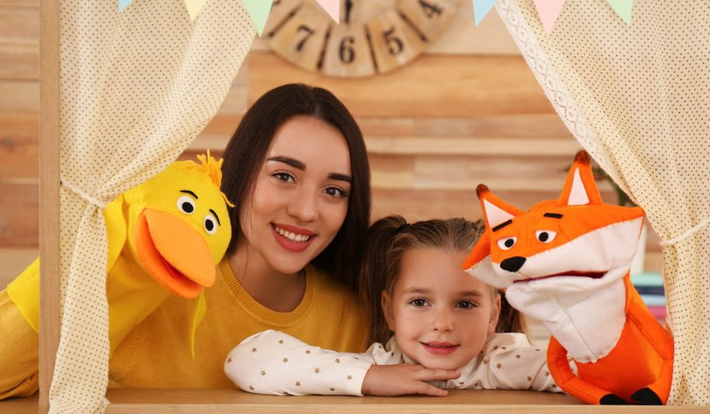 Mother and daughter performing puppet show at home