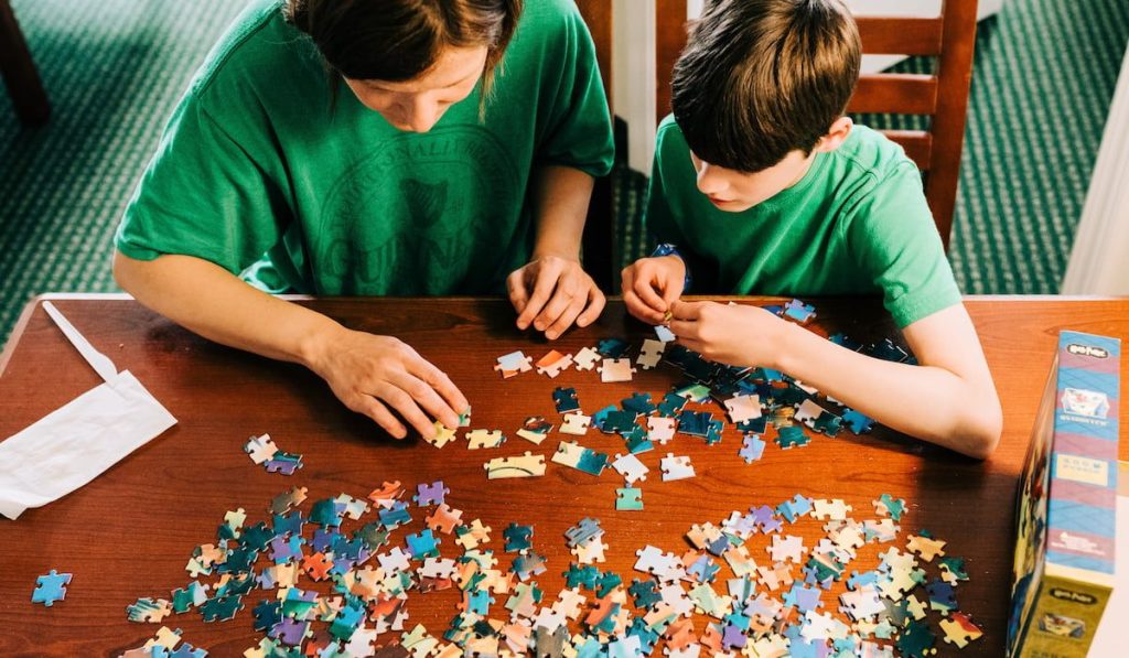 A mom and her son attempt to put together a puzzle