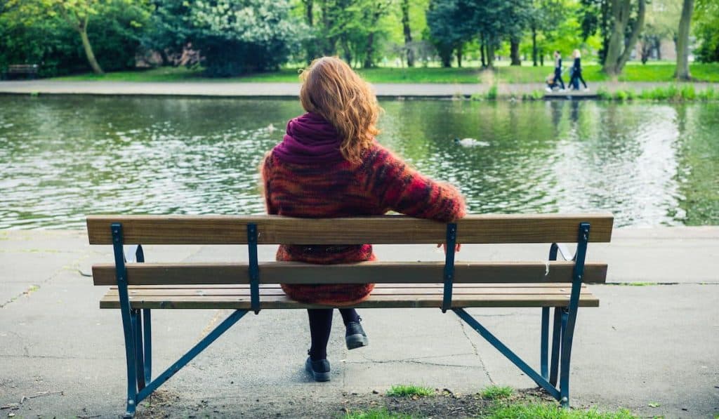 woman relaxing on the bench by the pond