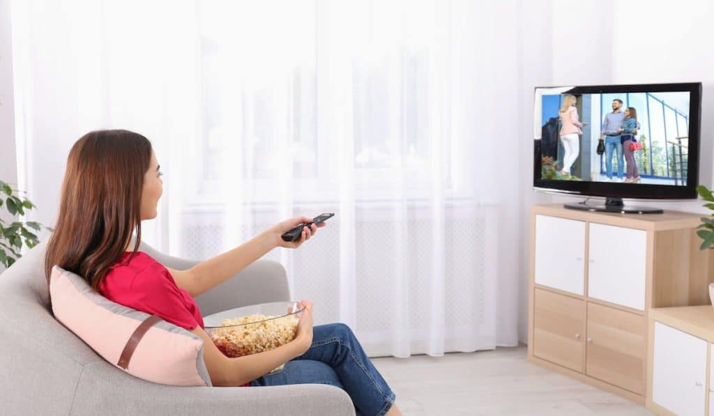 woman watching TV on sofa at home