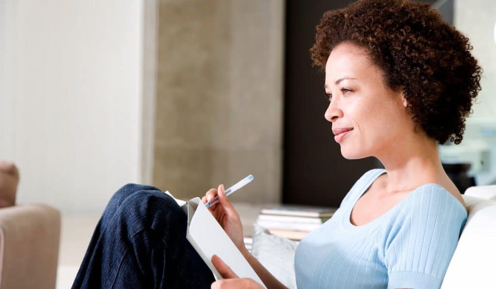 Woman writing a diary or journal, relaxing at home