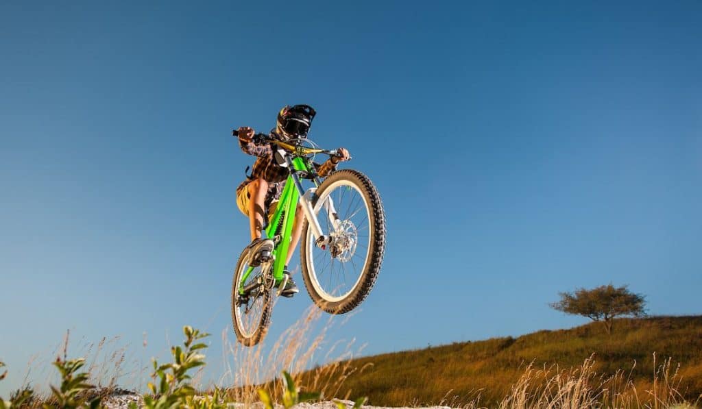 Athlete bicyclist in helmet jumping on a mountain bike on the hill 