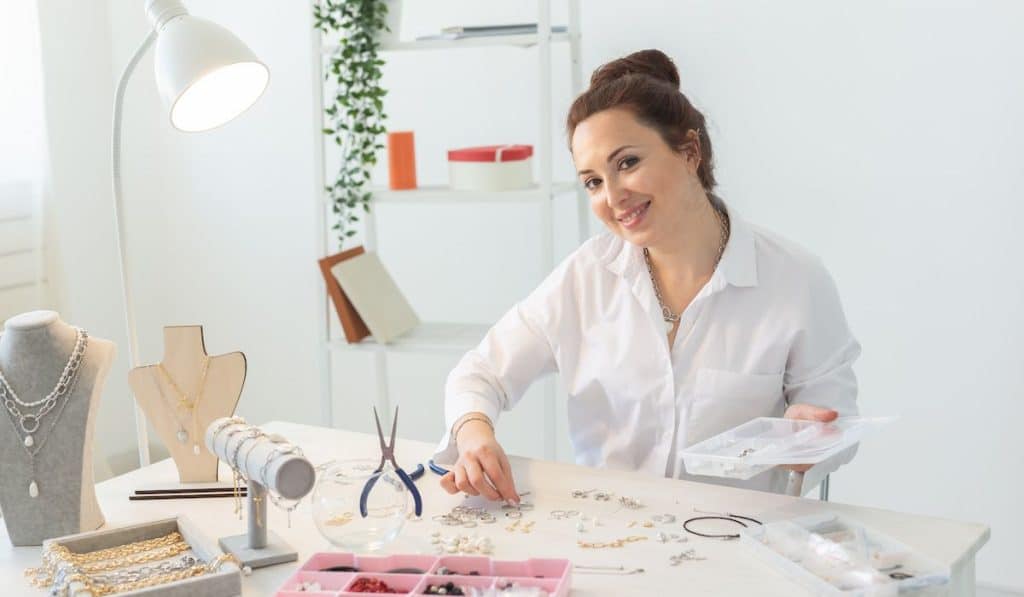 Beautiful jewelry designer making handmade jewelry in her home workshop