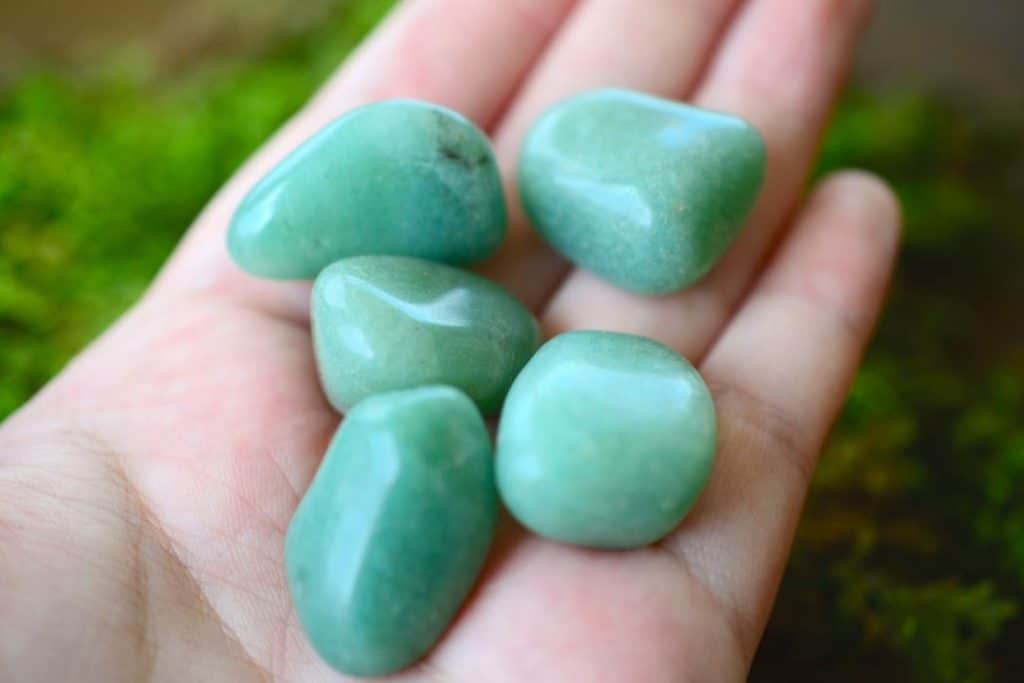 Beautiful tumbled green quartz, female hand holding tumbled semi-precious green quartz