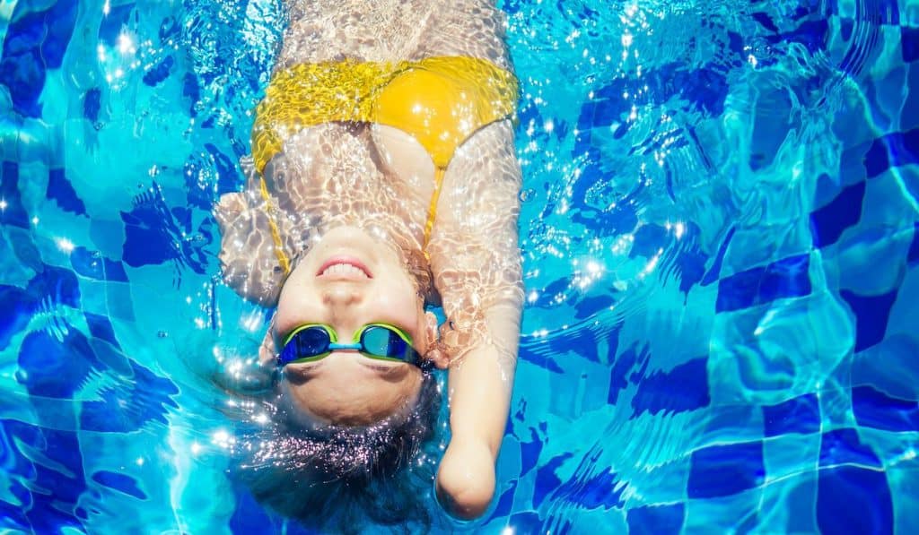 Beautiful young armless woman training to swim in pool