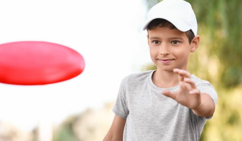 Cute little boy playing frisbee outdoors