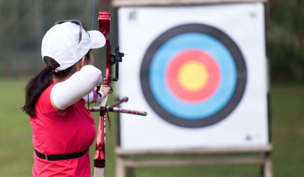 Female athlete practicing archery in stadium