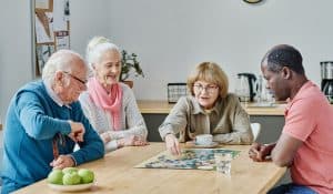 group of senior people sitting at table and playing board games together