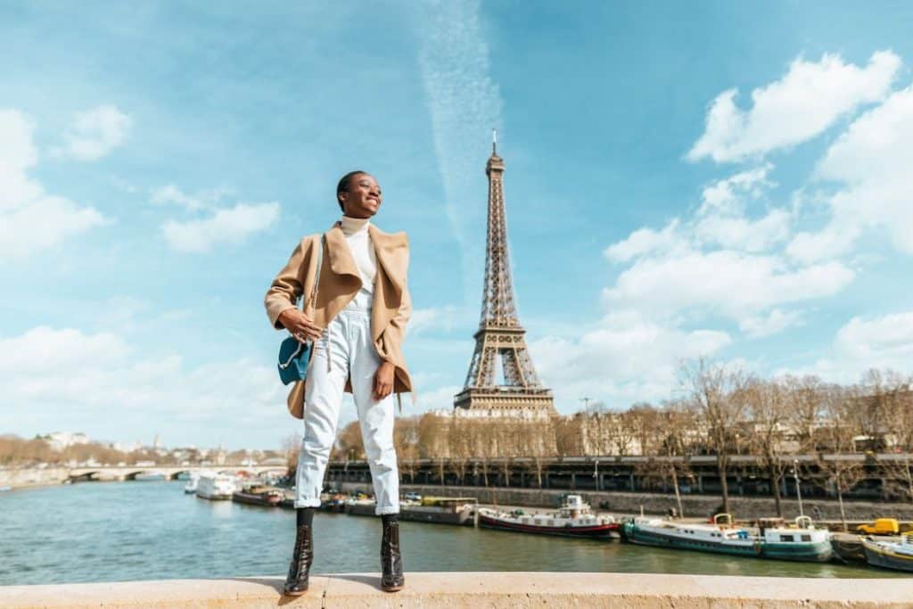 Happy woman posing on a bridge with the Eiffel tower on the background in Paris France