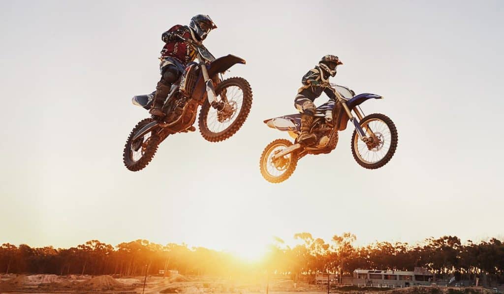 Jumping over the sunset. Two motocross riders in midair during a race 