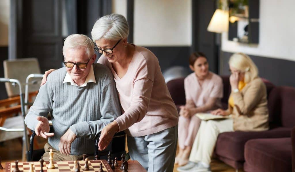 Portrait of two senior playing chess and enjoying activities in retirement home