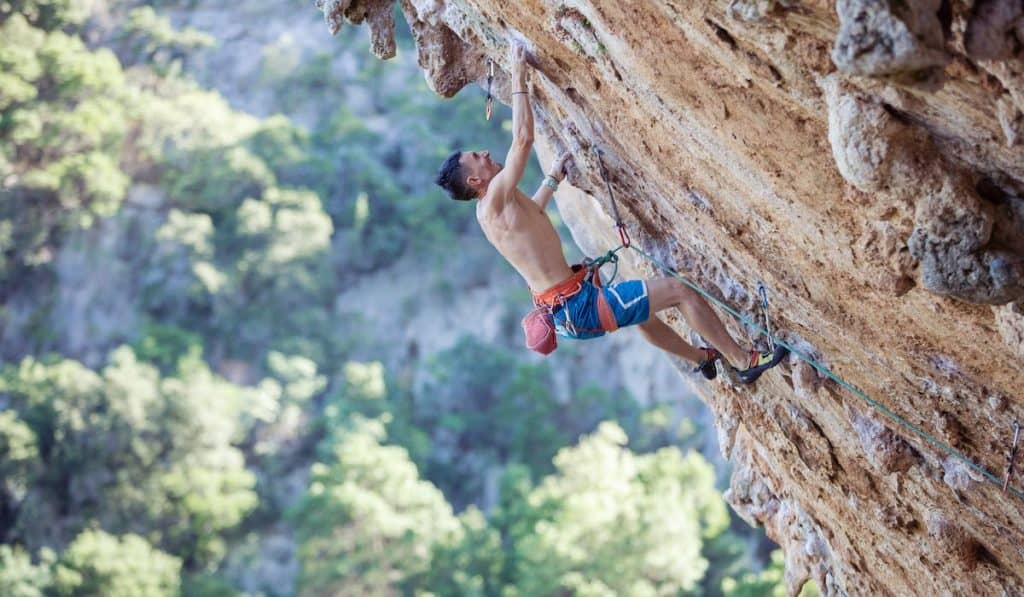 Rock climber on challenging route on overhanging cliff