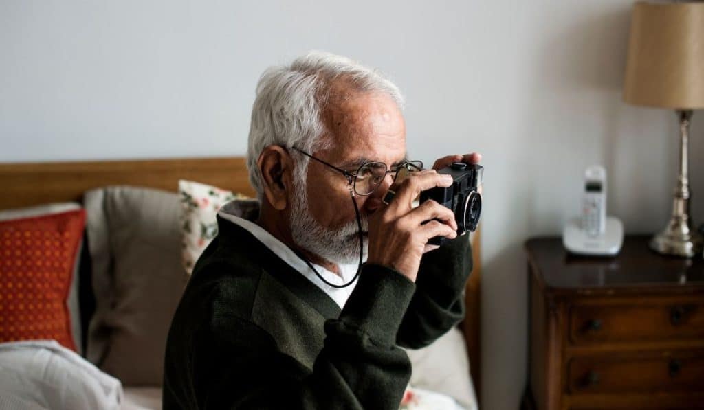 Senior man at the retirement house taking photo with his camera