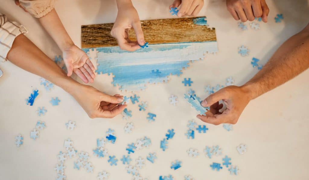 Top view of family's hand solving jigsaw puzzle together at home