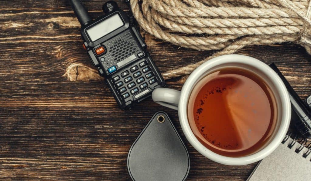 Tourist set with walkie talkie, rope. cup of tea on wooden background