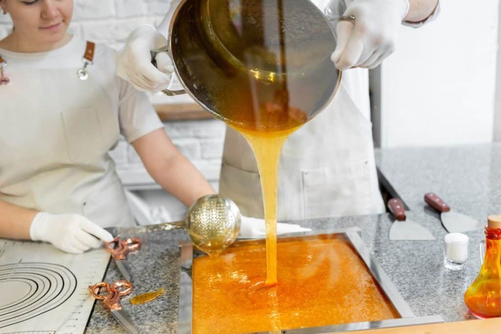 Two young woman making candy caramel, pouring caramel on the table
