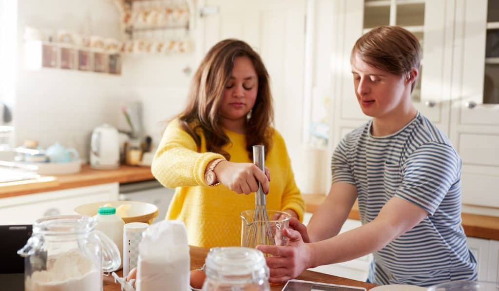 Young couple with down syndrome baking in the kitchen at home