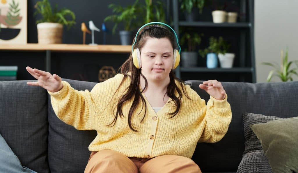 Young woman with disability enjoying dance music sitting on the sofa