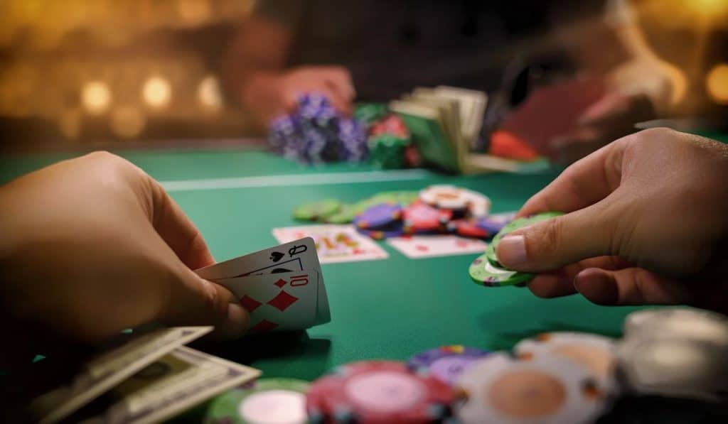 hand of a man holding Cards and poker coins playing poker game at the casino