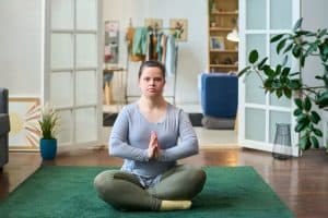 woman with disability sitting in pose of lotus on the floor living room practicing yoga
