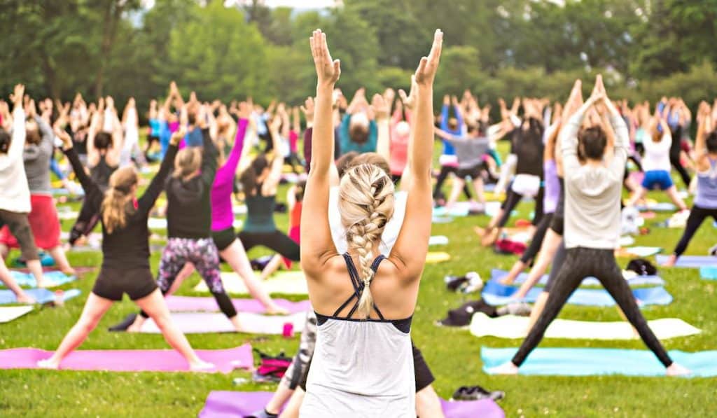 big group of adults attending a yoga class outside in park