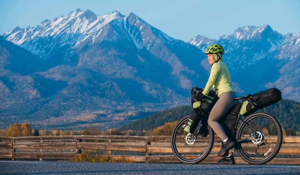 The woman travel on mixed terrain cycle touring with bikepacking.