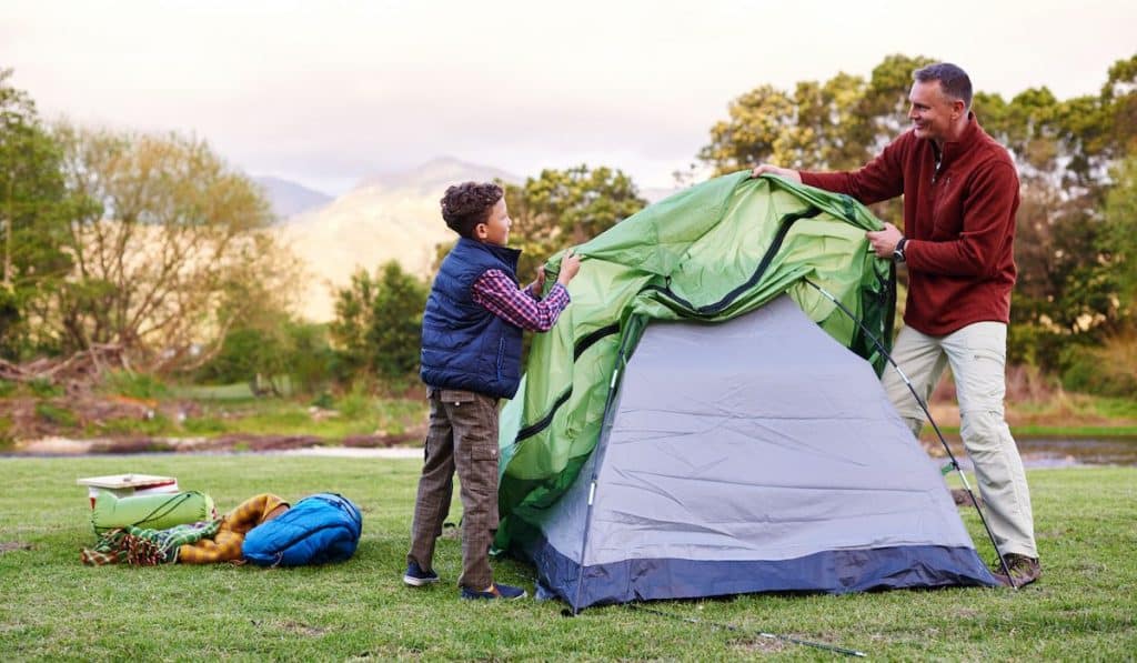 father and son setting up a tent together while camping
